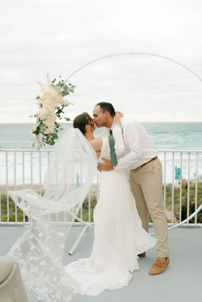 Bride and groom having their first kiss at Boca Highland Beach Club