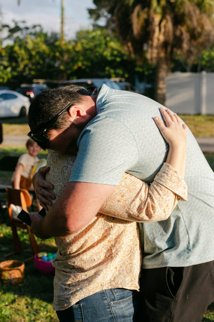 Couple tightly hugging after Patrick proposed at a family gathering in West Palm Beach Florida