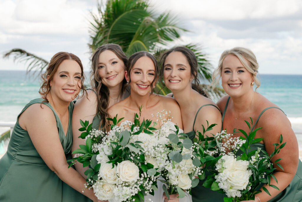 bride with her bridesmaids posing in front of the beach